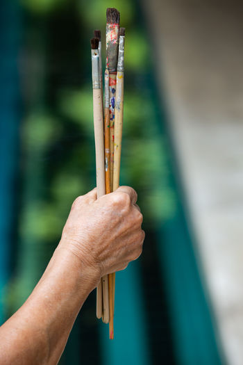 Close-up of hand holding paintbrushes