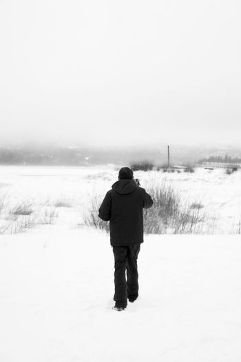 Rear view of man standing on snow covered field