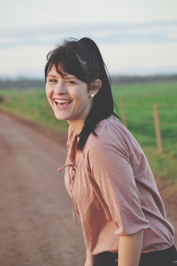 Portrait of smiling young woman standing on road