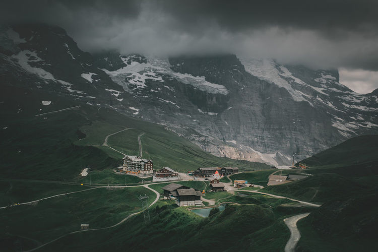 Aerial view of mountain range with low-hanging clouds and buildings in valley in switzerland