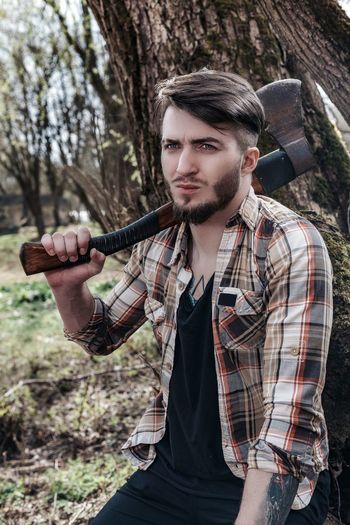 Young man holding weapon in forest