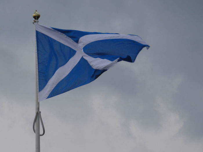 Low angle view of scottish flag against cloudy sky