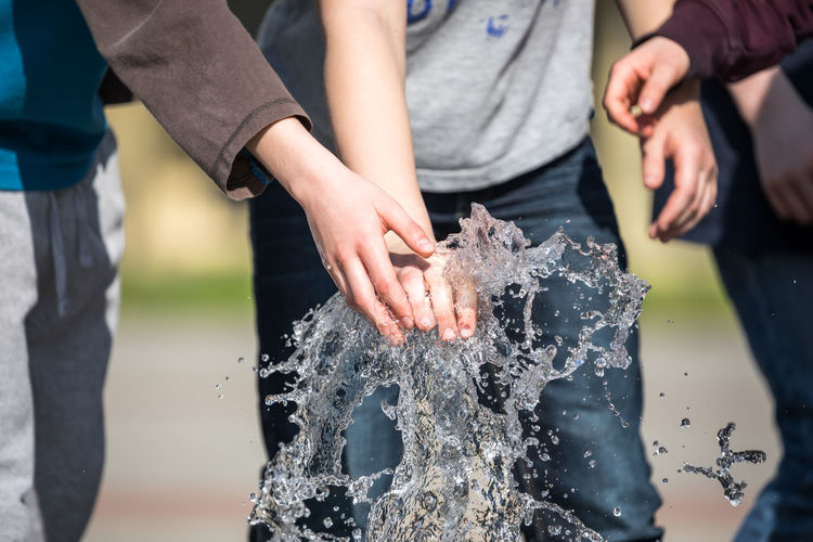 Midsection of children playing with fountain