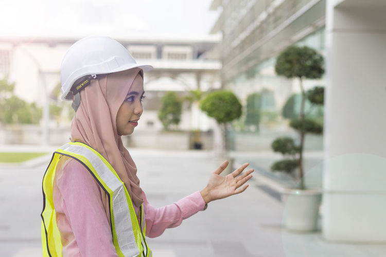 Female architect gesturing while standing on street outside office building