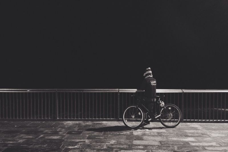 Man riding bicycle on footpath against wall at night