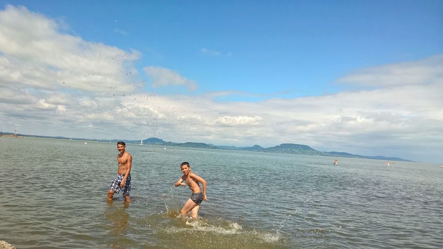 Siblings enjoying summer in lake balaton against sky