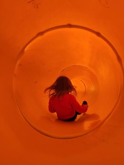 Rear view of little girl in a orange slider