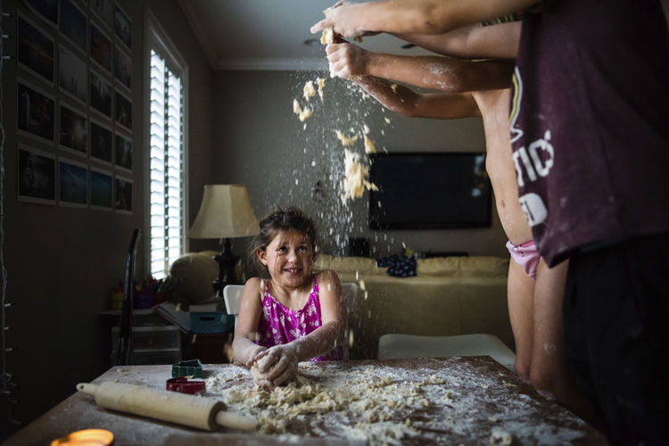 Siblings playing with flour and dough while making cookie during christmas at home