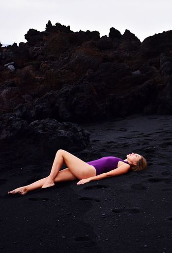 Woman laying on black volcanic sandy beach on la palma canary island in spain