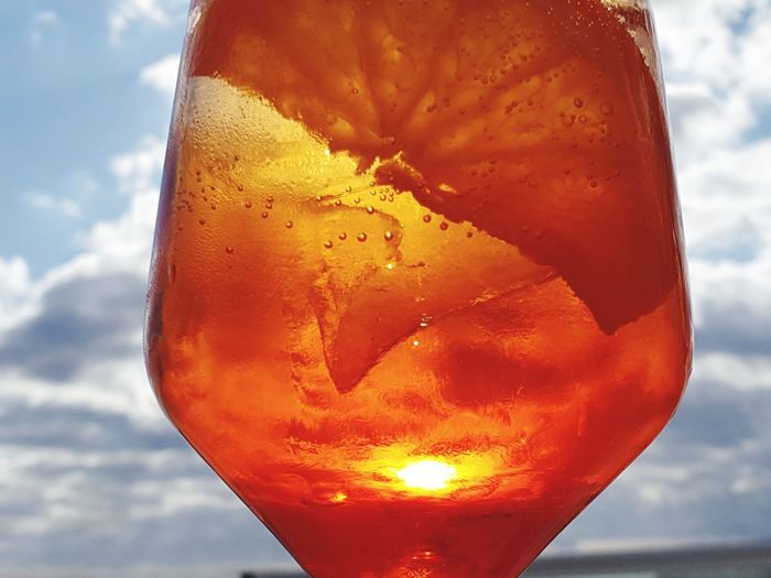 Close-up of orange drink against sky