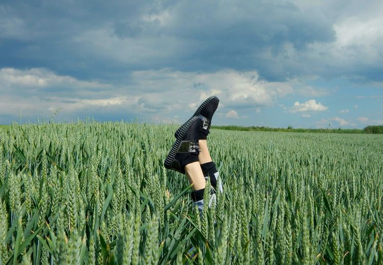 Woman handstanding in wheat field against sky