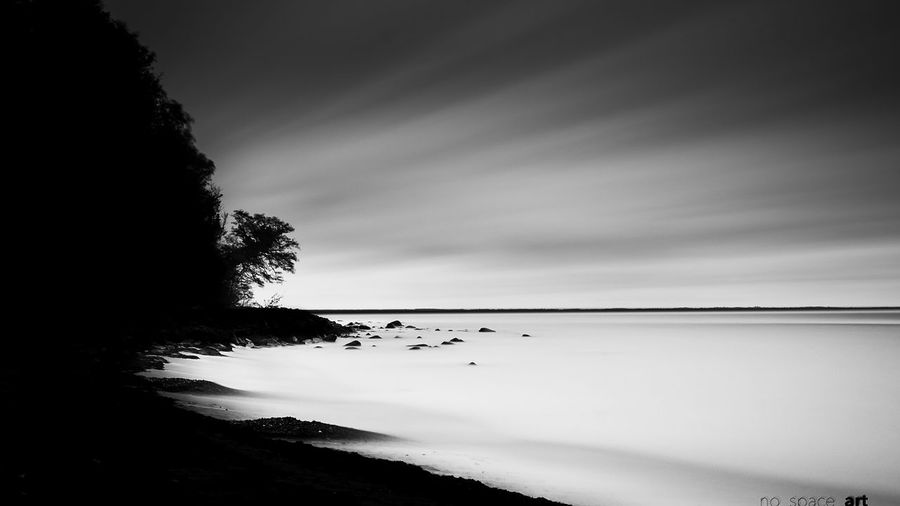 Silhouette trees on calm sea against the sky