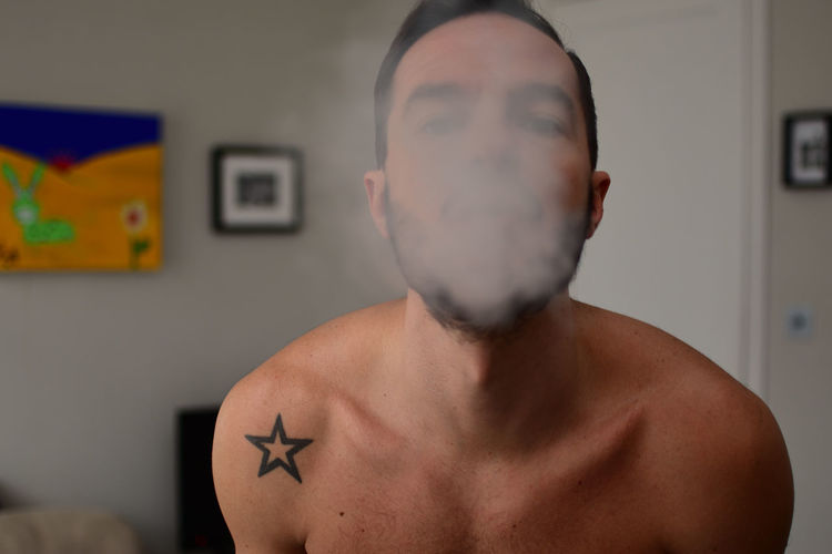 Portrait of man exhaling smoke at home
