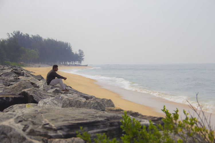 Solitary man sitting on rocks on the beach