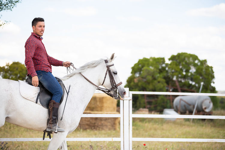 Mid adult man riding horse against sky