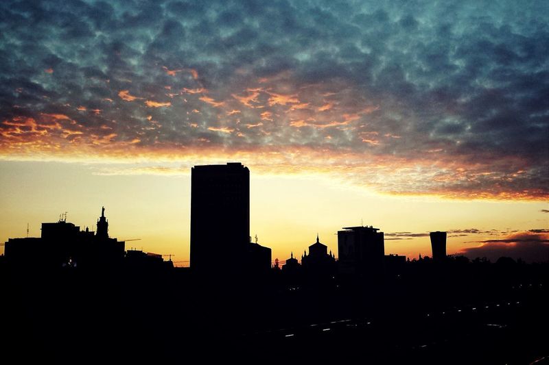 Silhouette of buildings against cloudy sky