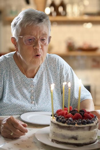 Grandmother blows candles on her birthday cake
