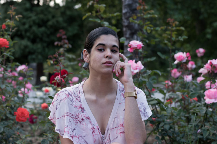 Portrait of young woman against rose plants at park