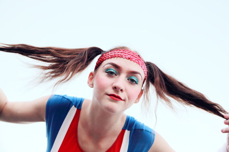Portrait of cheerleader pulling ponytails against white background