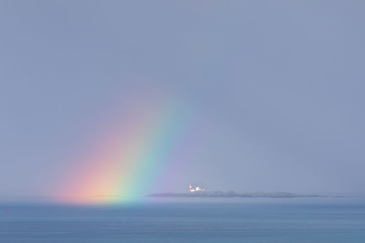 Scenic view of rainbow over sea against clear sky