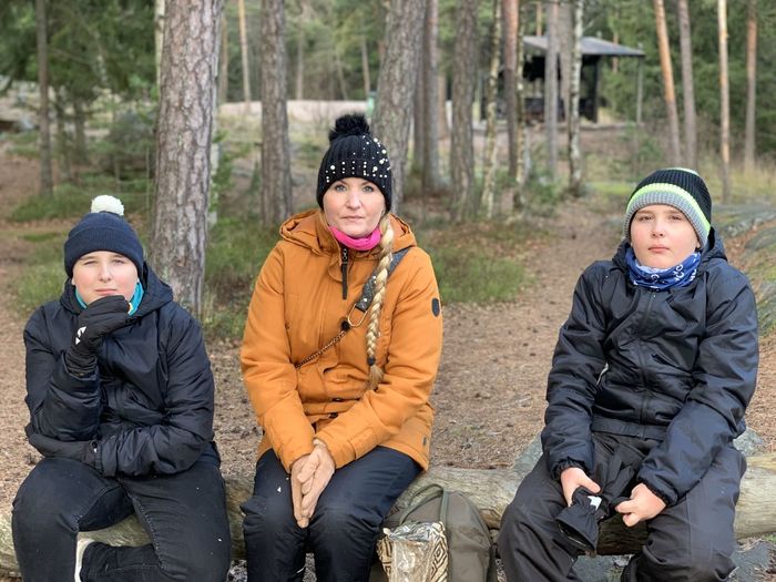 Portrait of mother and sons sitting in forest