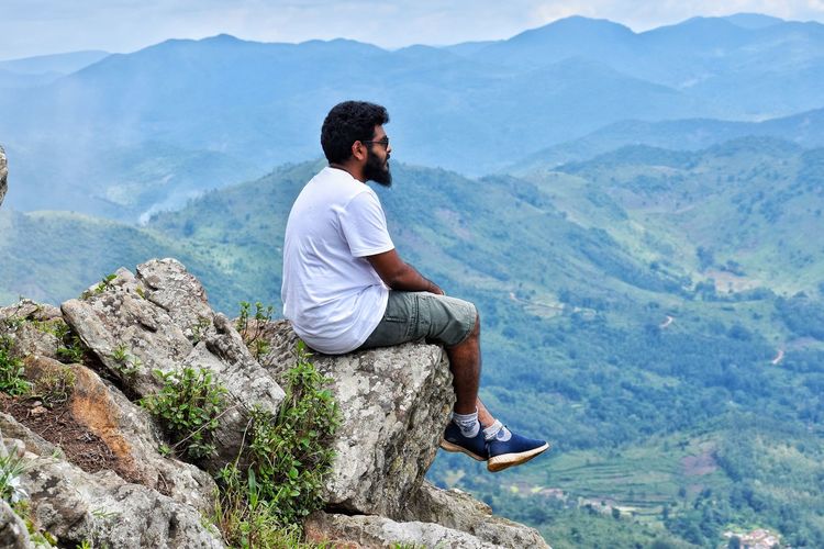 Man sitting on rock looking at mountains