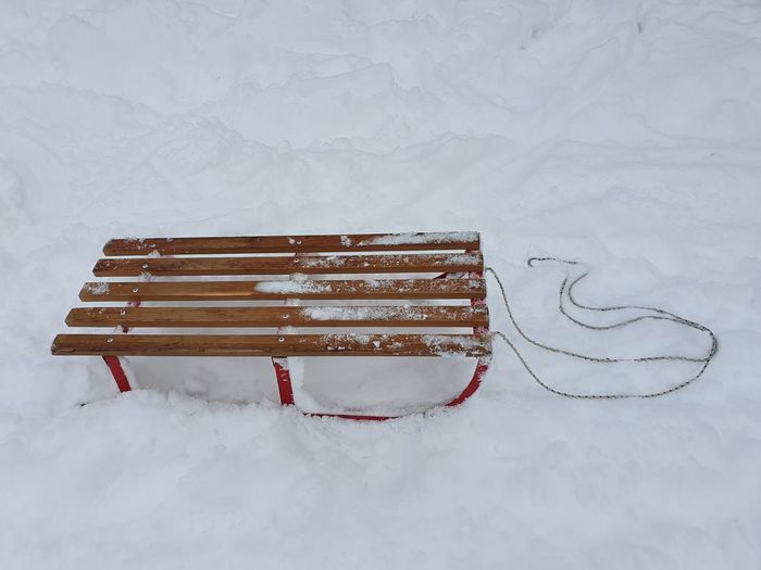 Close-up of frozen bench on snow covered field