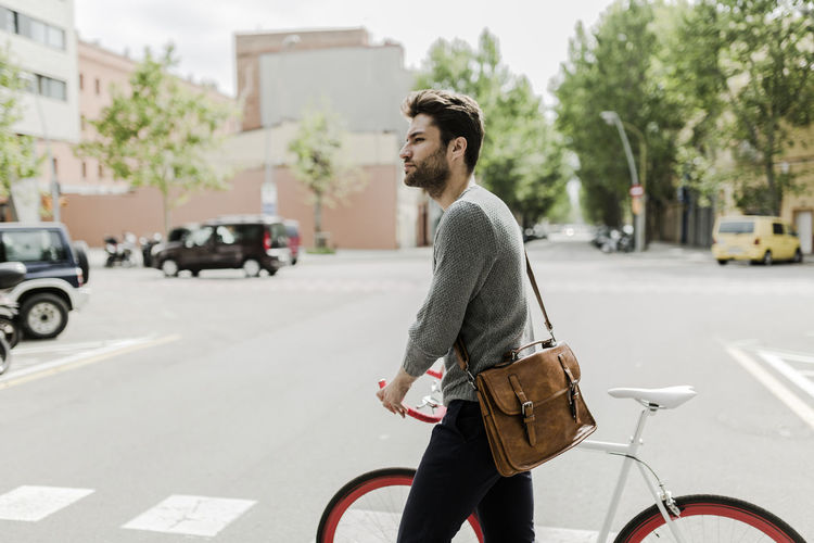 Side view of young man riding bicycle on city street
