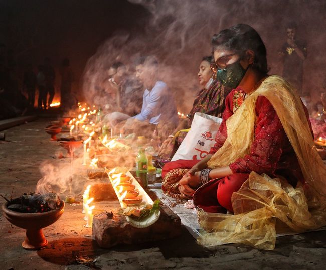 Girl doing prayer at barodi lokhnath brahmachari ashram infront of burning candle and diya