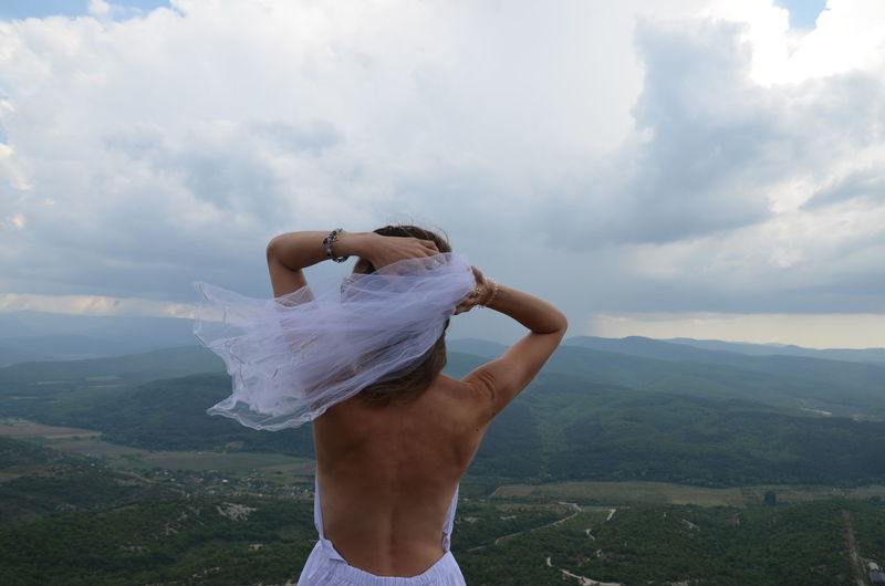 Midsection of woman standing on mountain against sky