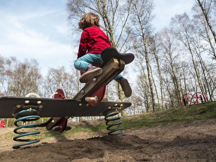 Low angle view of boy playing on seesaw at playground