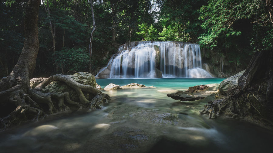 Epic waterfall smooth flowing water with emerald green pond in rainforest. erawan falls, thailand.