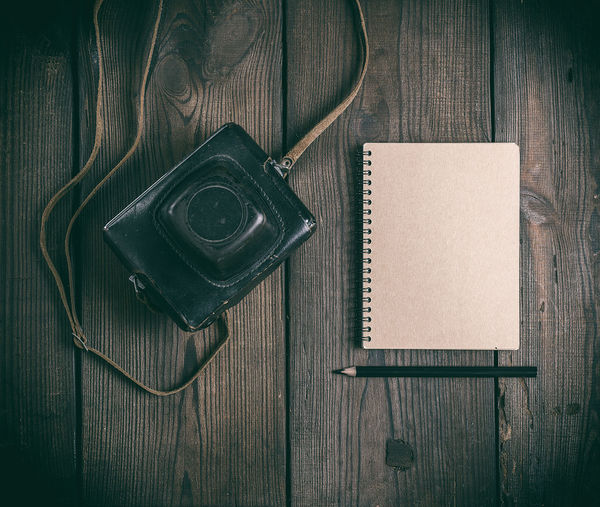 High angle view of camera and spiral notebook on table