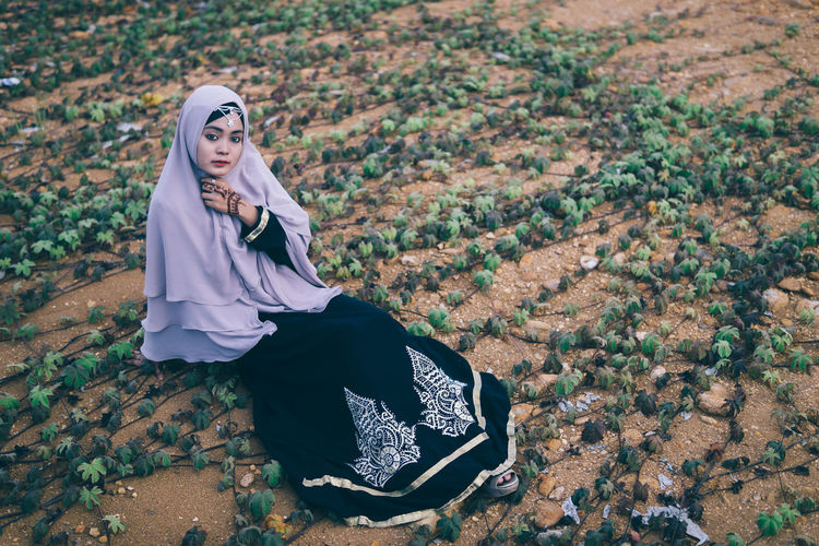 Portrait of young woman in hijab sitting outdoors