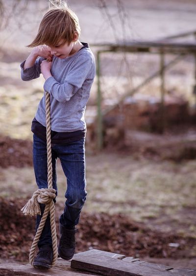 Boy holding rope while standing on land