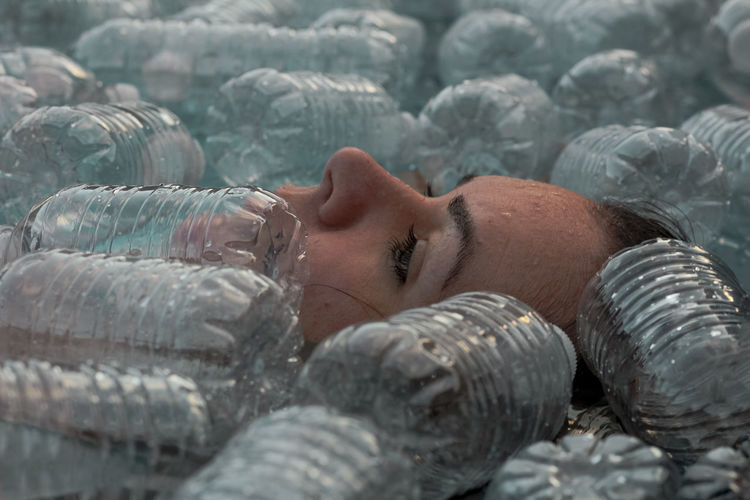 Portrait of woman surrounded  by plastic water bottles 