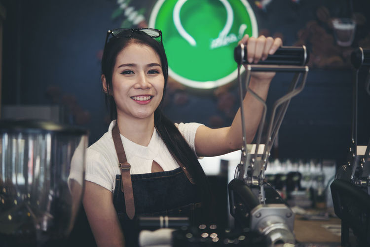 Portrait of smiling female barista working at cafe