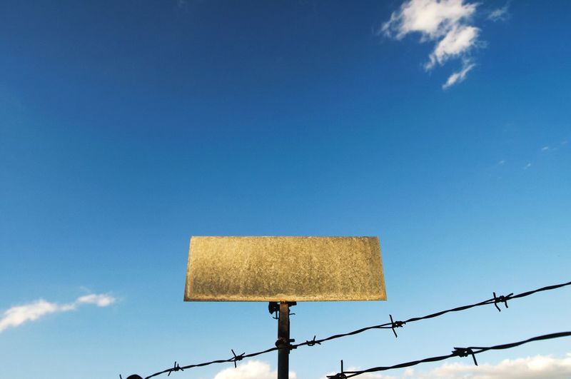 Low angle view of sign against blue sky