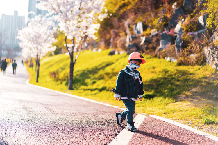 Rear view of boy walking on road in city