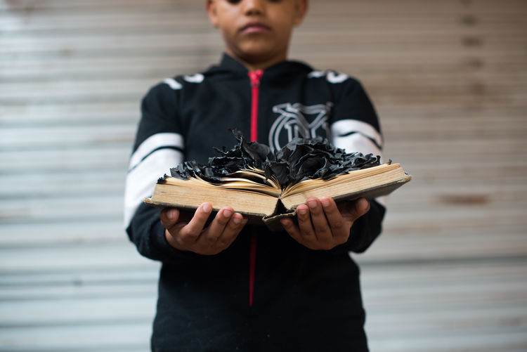Conceptual portrait of a boy holding a burnt book