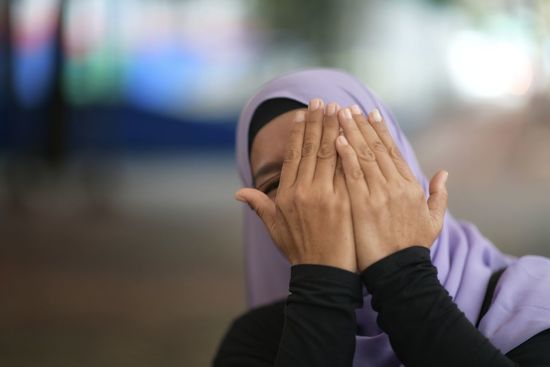 Close-up of woman covering face with hands