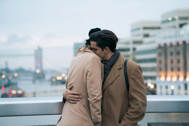 Couple in warm clothing embracing while standing in balcony