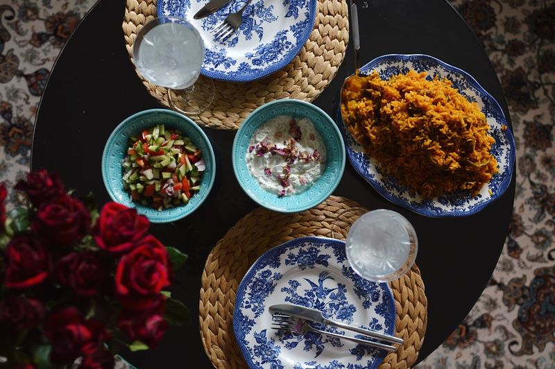 High angle view of flowers, food, plates on table