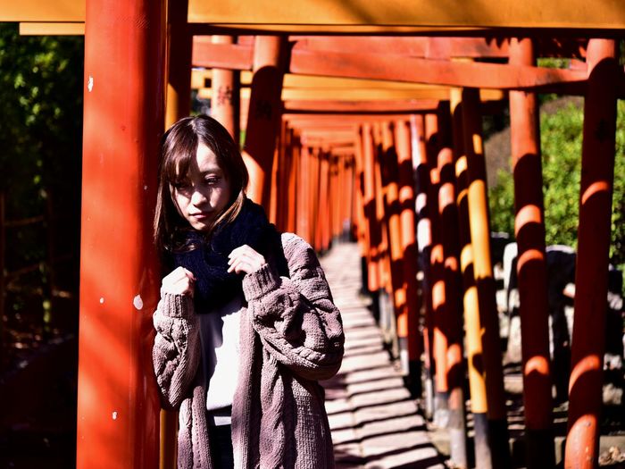 Portrait of woman standing by torii gate