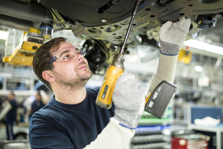Man working at car underbody in modern factory