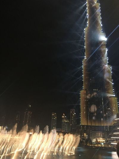 Illuminated fountain against buildings at night