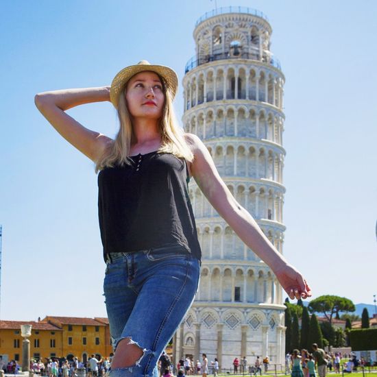 Low angle of young woman standing against leaning tower of pisa