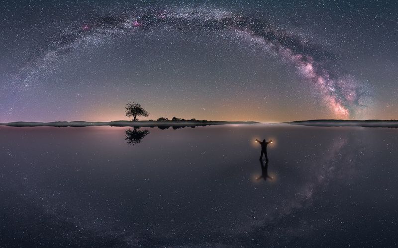 Silhouette man standing in lake against star field at night