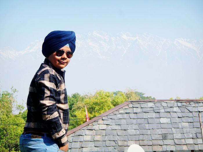 Teenage boy wearing turban and sunglasses while standing against sky