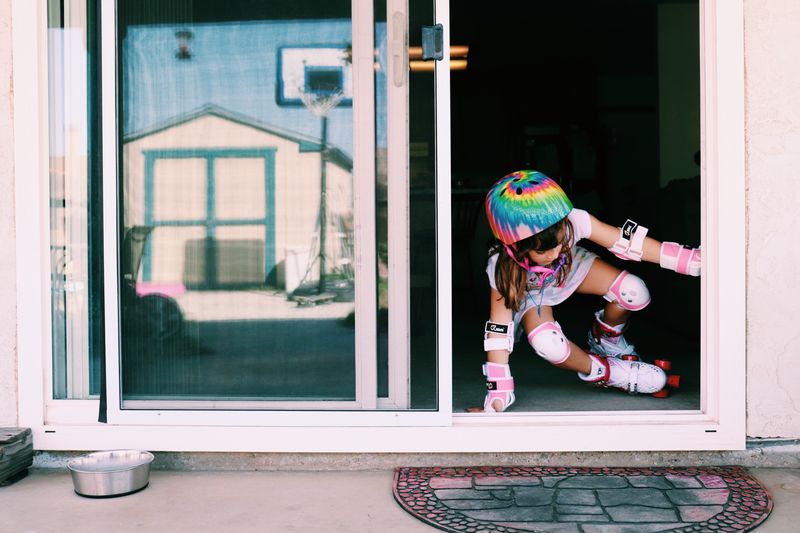 Full length of girl skating in front of door
